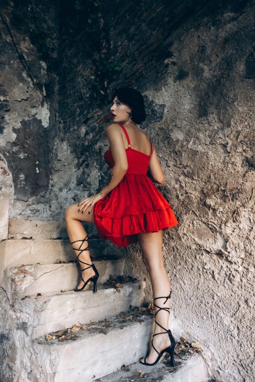 A woman in a red dress and high heels is standing on some stairs