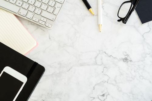 Free Flat lay of a modern office desk with gadgets and stationery on a marble surface. Stock Photo