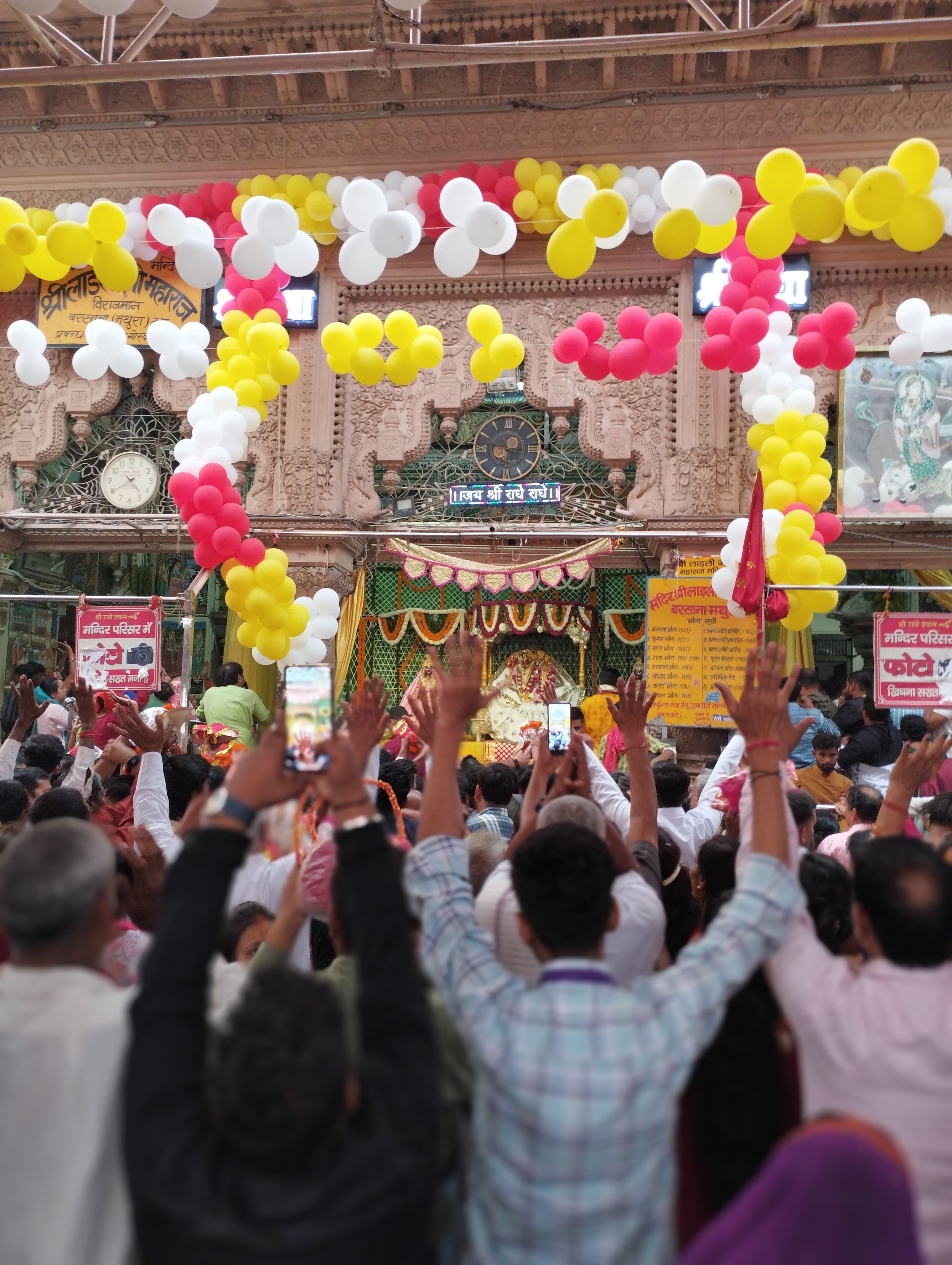 Vibrant temple ceremony with a crowd celebrating under colorful balloons in a Hindu cultural setting.