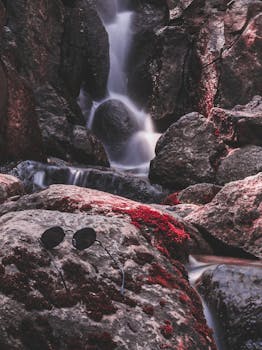 瀑布宁静地流过苔藓覆盖的岩石，石头上架着一副太阳镜