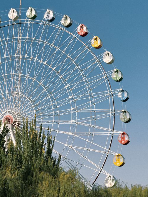 Free A vibrant Ferris wheel with colorful cabins set against a clear blue sky. Stock Photo
