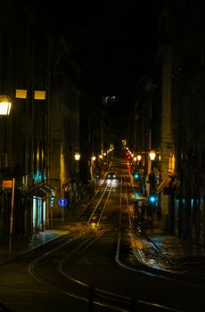 Scenic nighttime view of a quiet street in Lisbon, Portugal, highlighted by glowing streetlights.