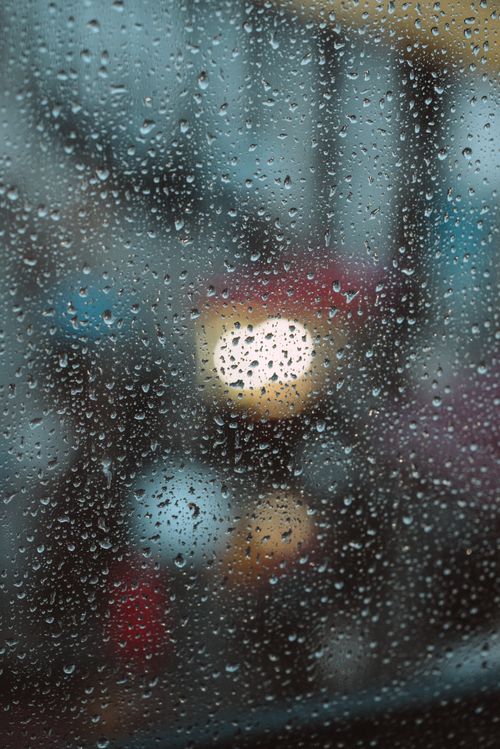 Free Blurry city lights seen through raindrop-covered window, creating an abstract feel. Stock Photo