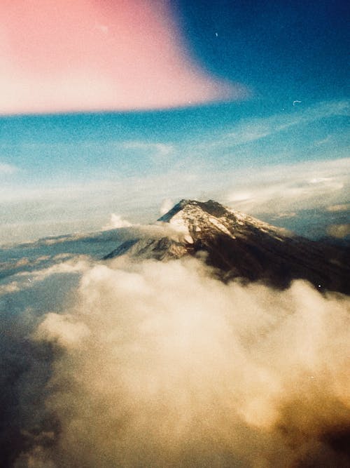 Aerial View of a Snow Covered Volcano Peak Among Clouds