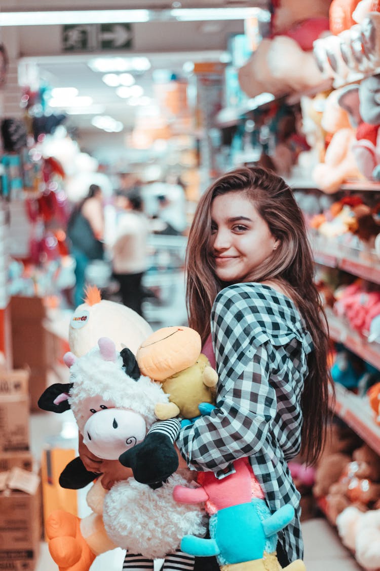 Smiling Woman In Check Shirt Holding Toys In Store