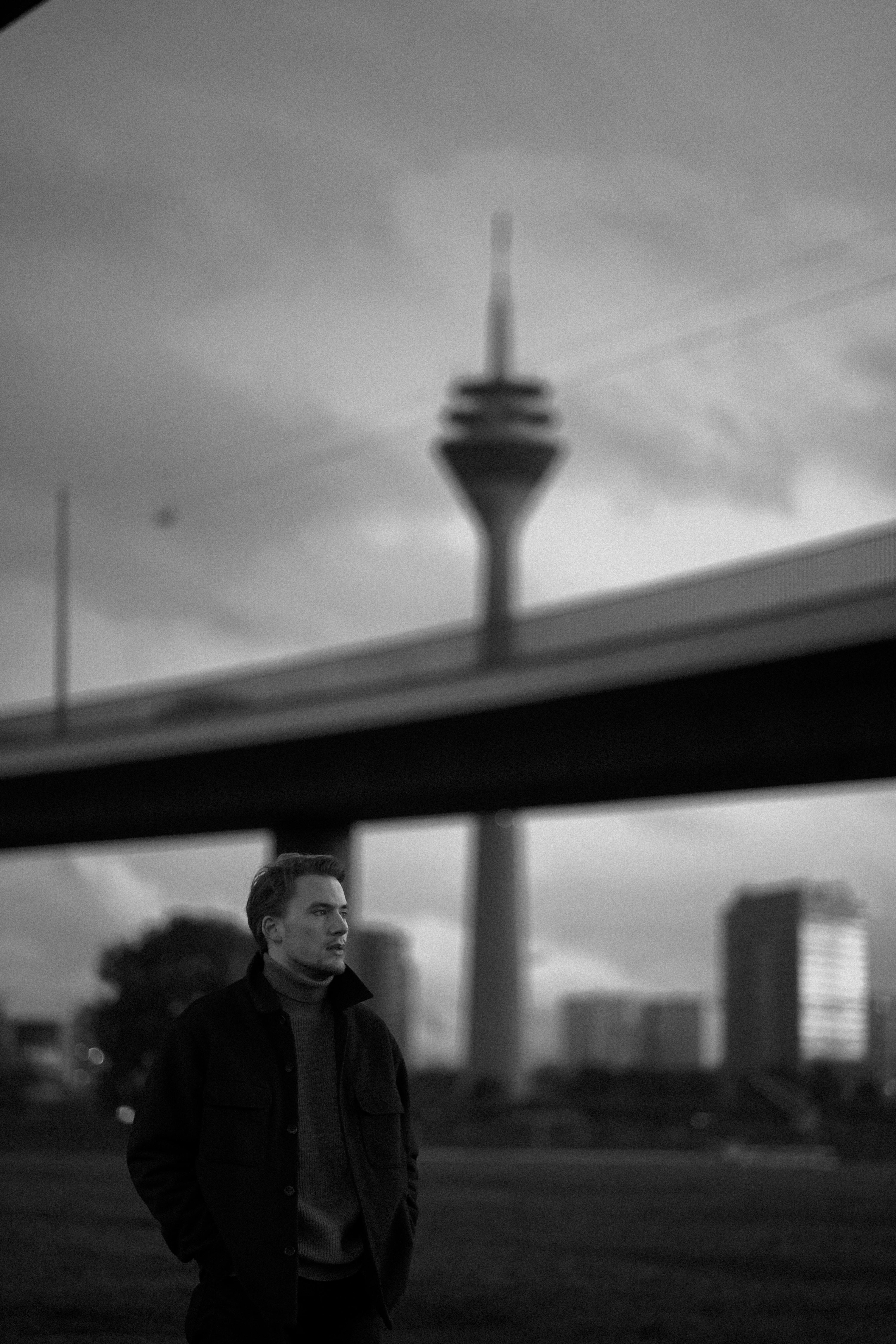 Urban portrait of a man in front of Düsseldorf's iconic tower in monochrome.