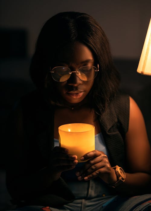 Woman in Eyeglasses Sitting and Holding Candle