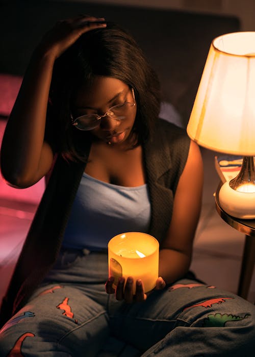 Woman in Eyeglasses Sitting and Holding Wax Candle