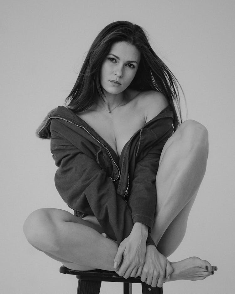 Woman In Jacket Sitting On Chair In Black And White