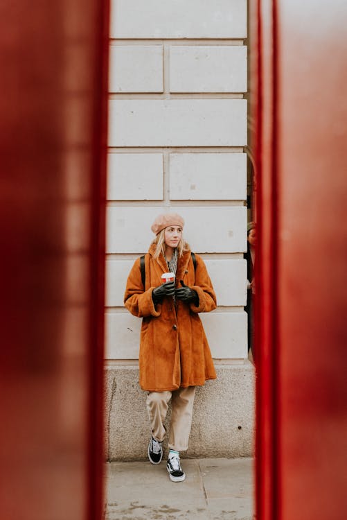 Woman Leaning on Wall While Holding Coffee Cup