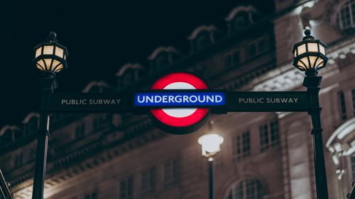 Free Illuminated London Underground sign with lamp posts at night. Stock Photo