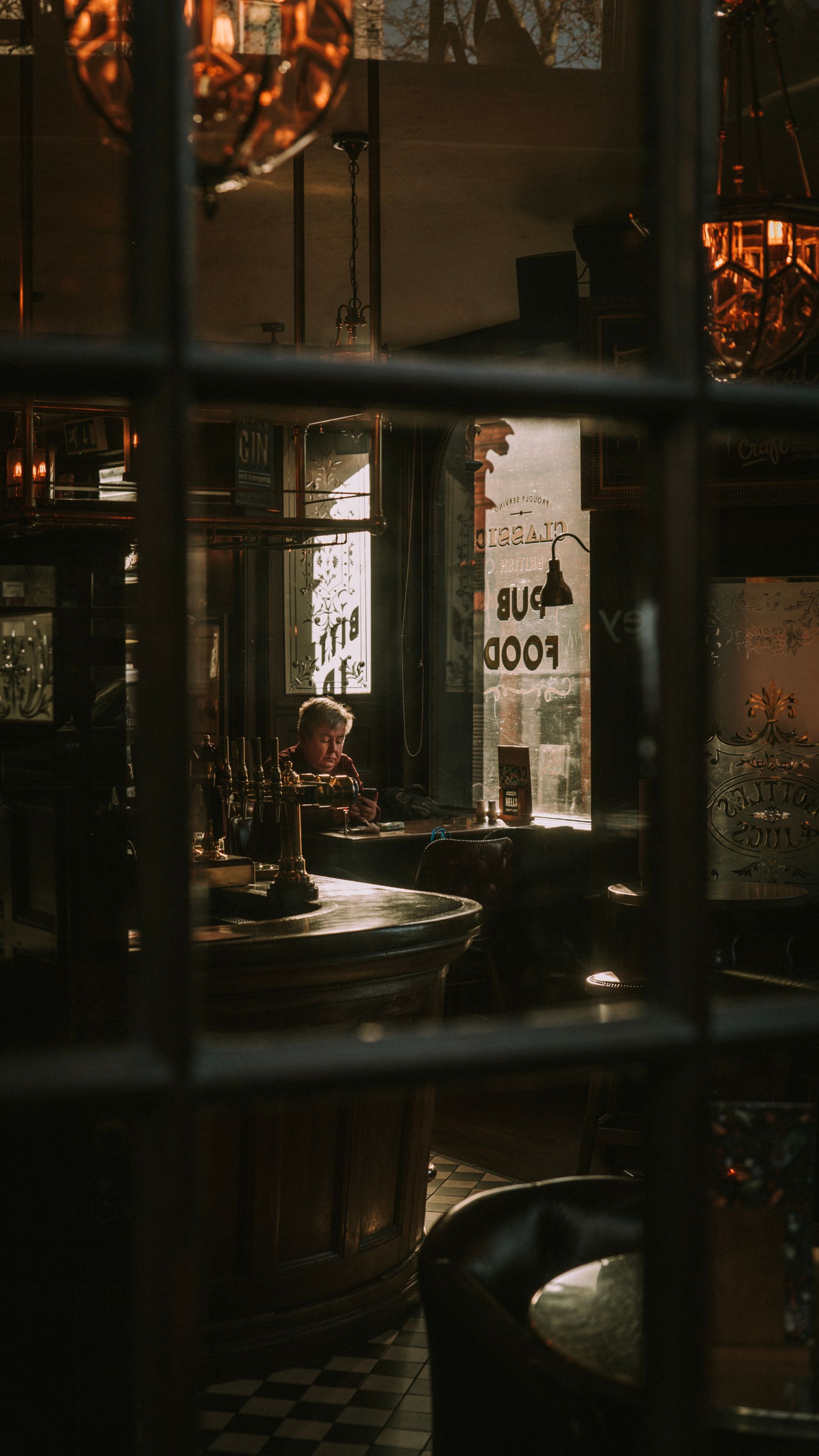 A warmly lit pub seen through its windows at dusk