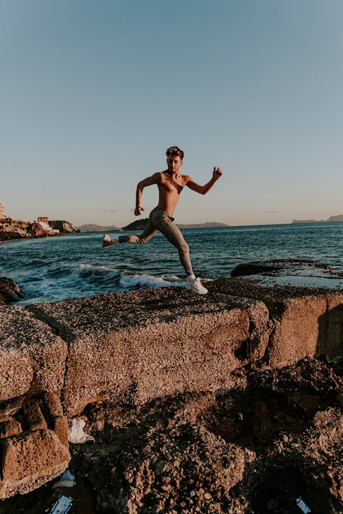 Free 海岸近くの茶色のバリケードを飛び越える男 Stock Photo