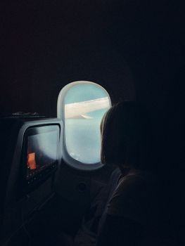 A person looks out an airplane window at the wing during a flight.