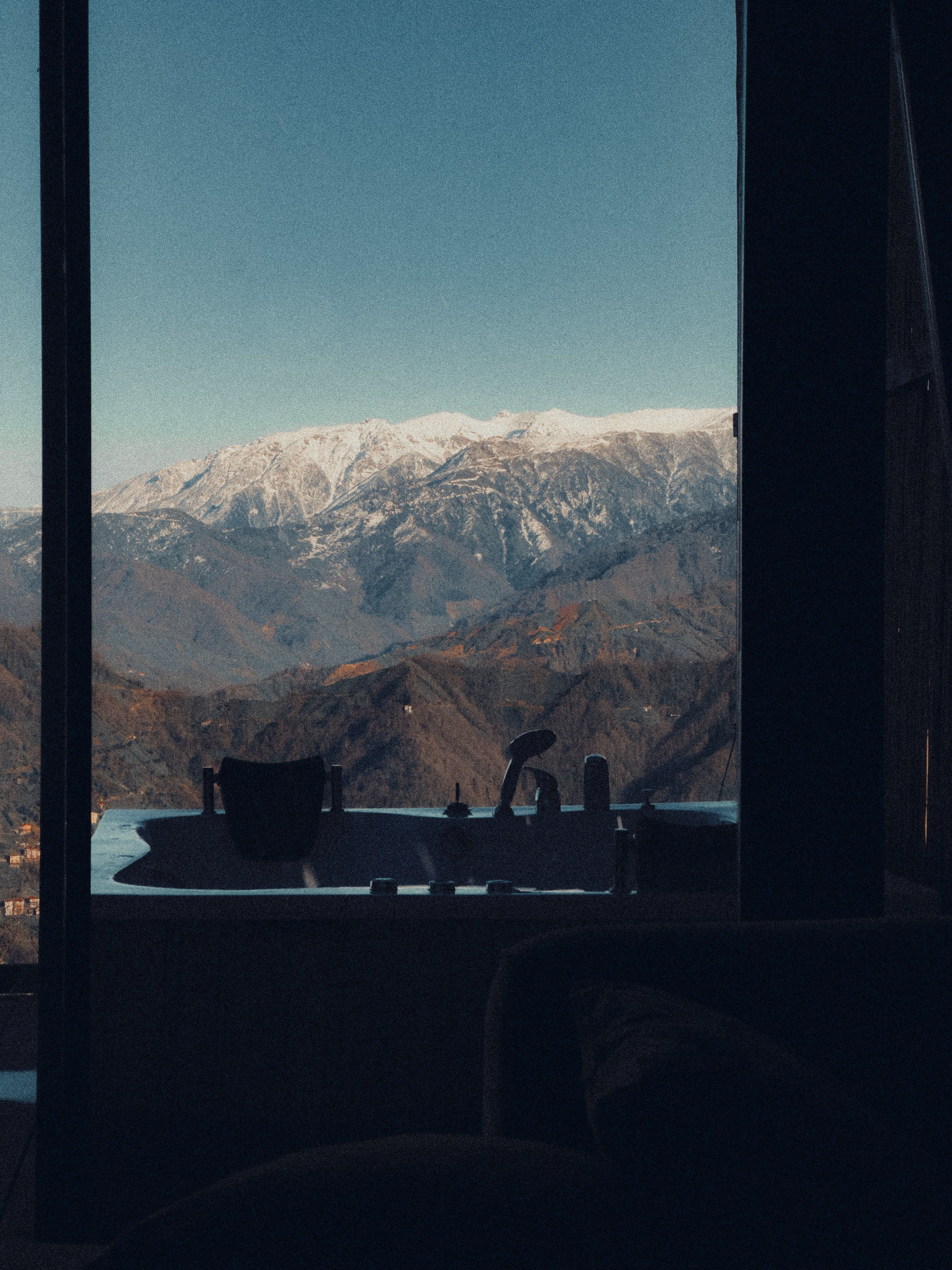 Relaxing view of snowy mountains from a luxurious indoor bathtub, perfect for unwinding.