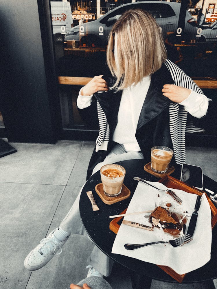 Woman Sitting At Cafe Table With Coffee And Pastry