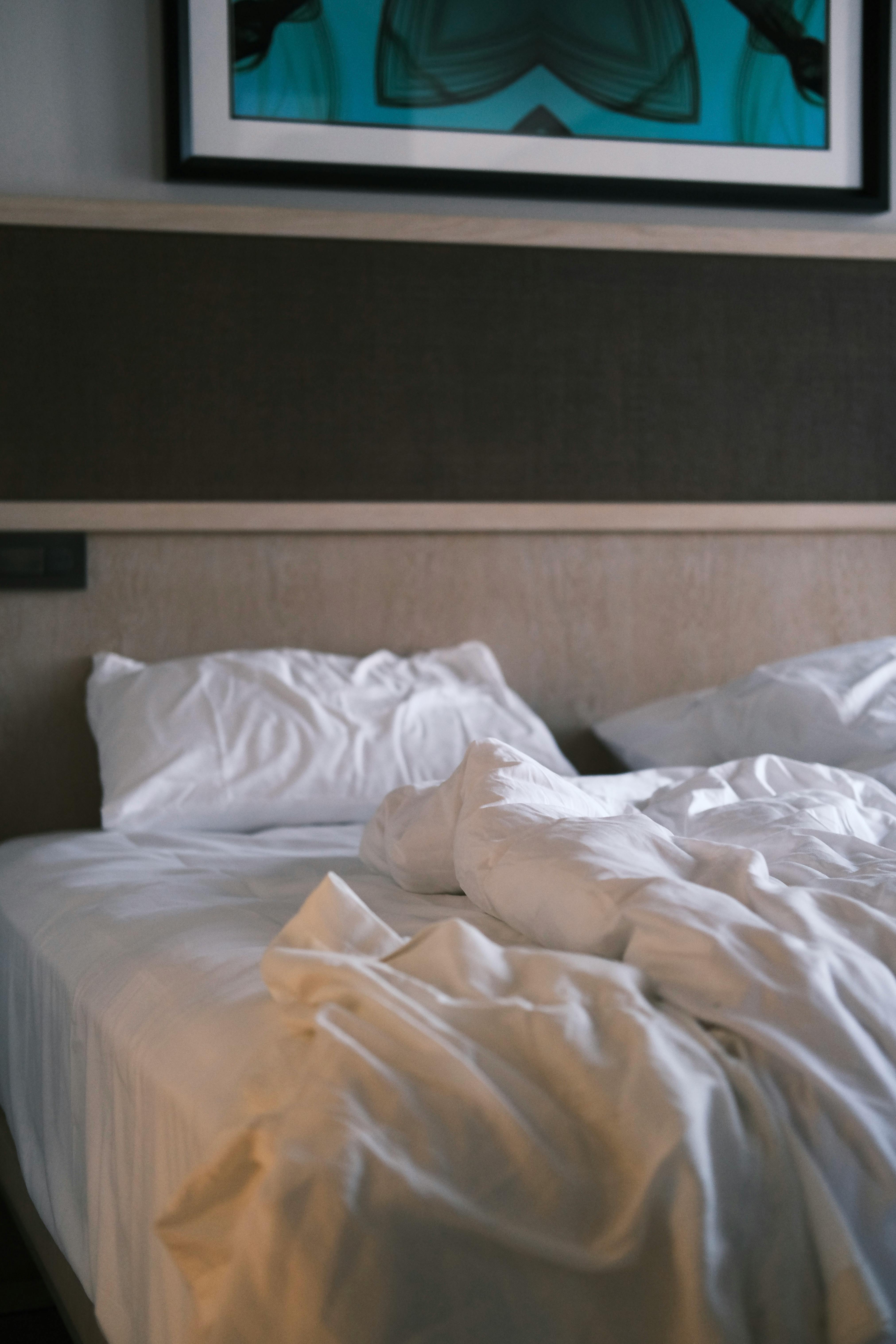 Inviting unmade bed with soft pillows in a stylish hotel room, ideal for comfort themes.