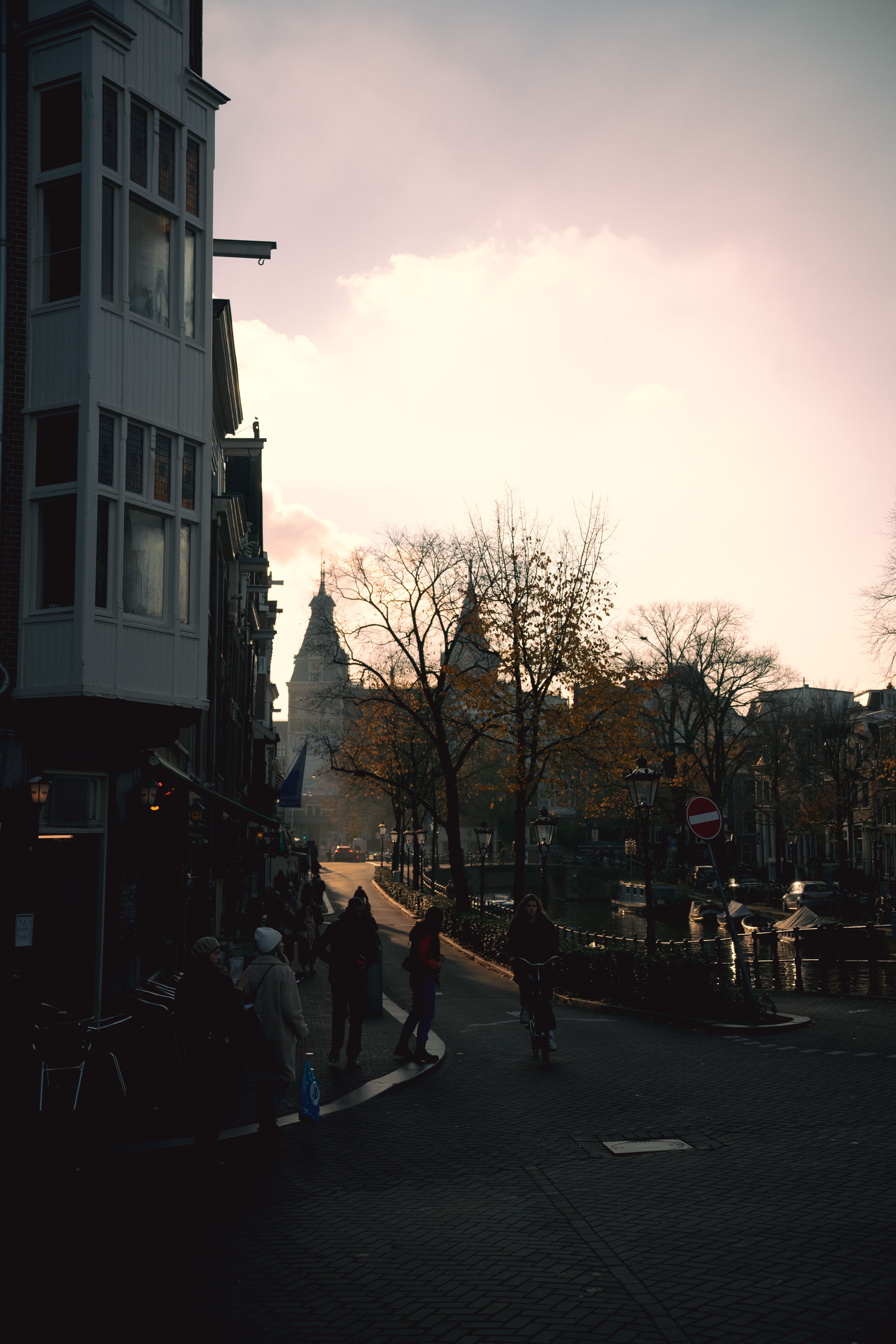 Silhouetted city scene in Amsterdam at sunset with iconic buildings and relaxed atmosphere.