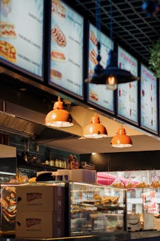 Bright interior of a fast food restaurant with digital menu displays and warm lighting.