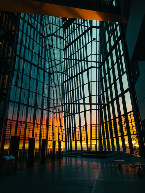 Free Stunning view of a modern architectural building with reflective glass panels during sunset, creating a silhouette effect. Stock Photo