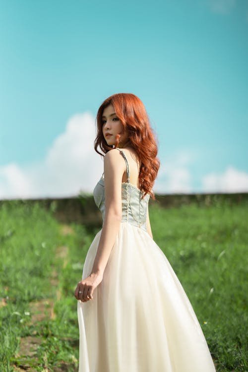 Woman in White Gown Standing on Grass under Blue Sky