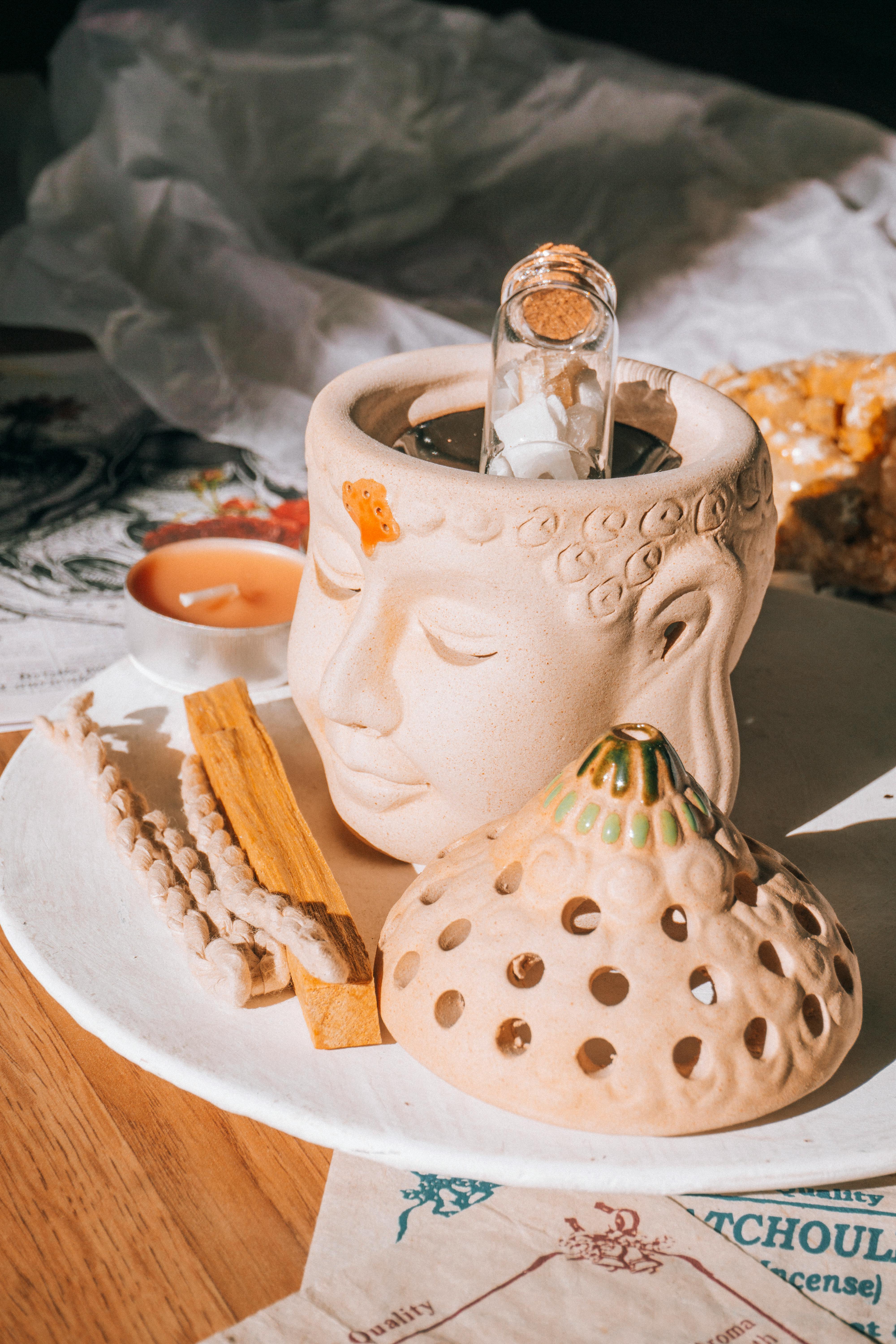 A serene arrangement featuring a Buddha-shaped incense holder, a candle, and natural elements, ideal for mindfulness practices.