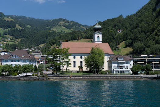 Picturesque church overlooking Lake Lucerne in Gersau, surrounded by lush mountains and serene water.