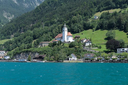 Discover the stunning Pfarrkirche Herz Jesu nestled in Flüelen, Switzerland, framed by lush green hills and Lake Lucerne.