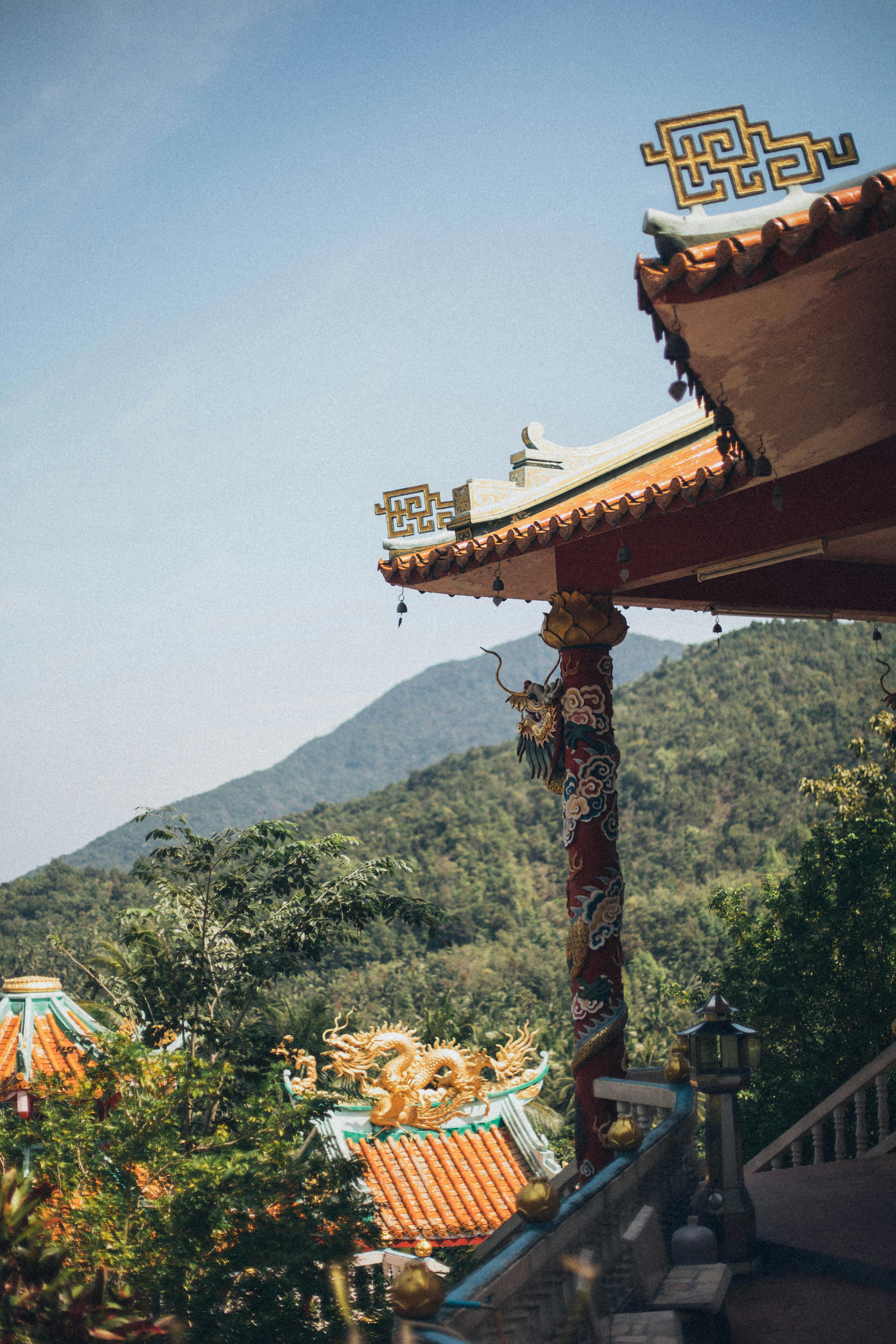 A serene traditional Asian temple with ornate architecture set against a mountain backdrop.