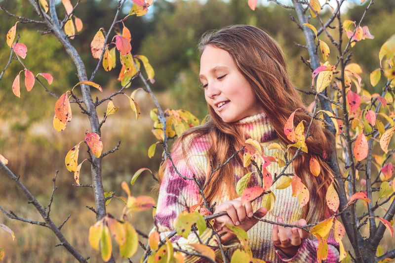 Woman in a turtleneck sweater among autumn branches