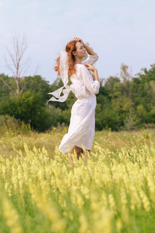 Woman in a White Dress Standing on a Meadow 