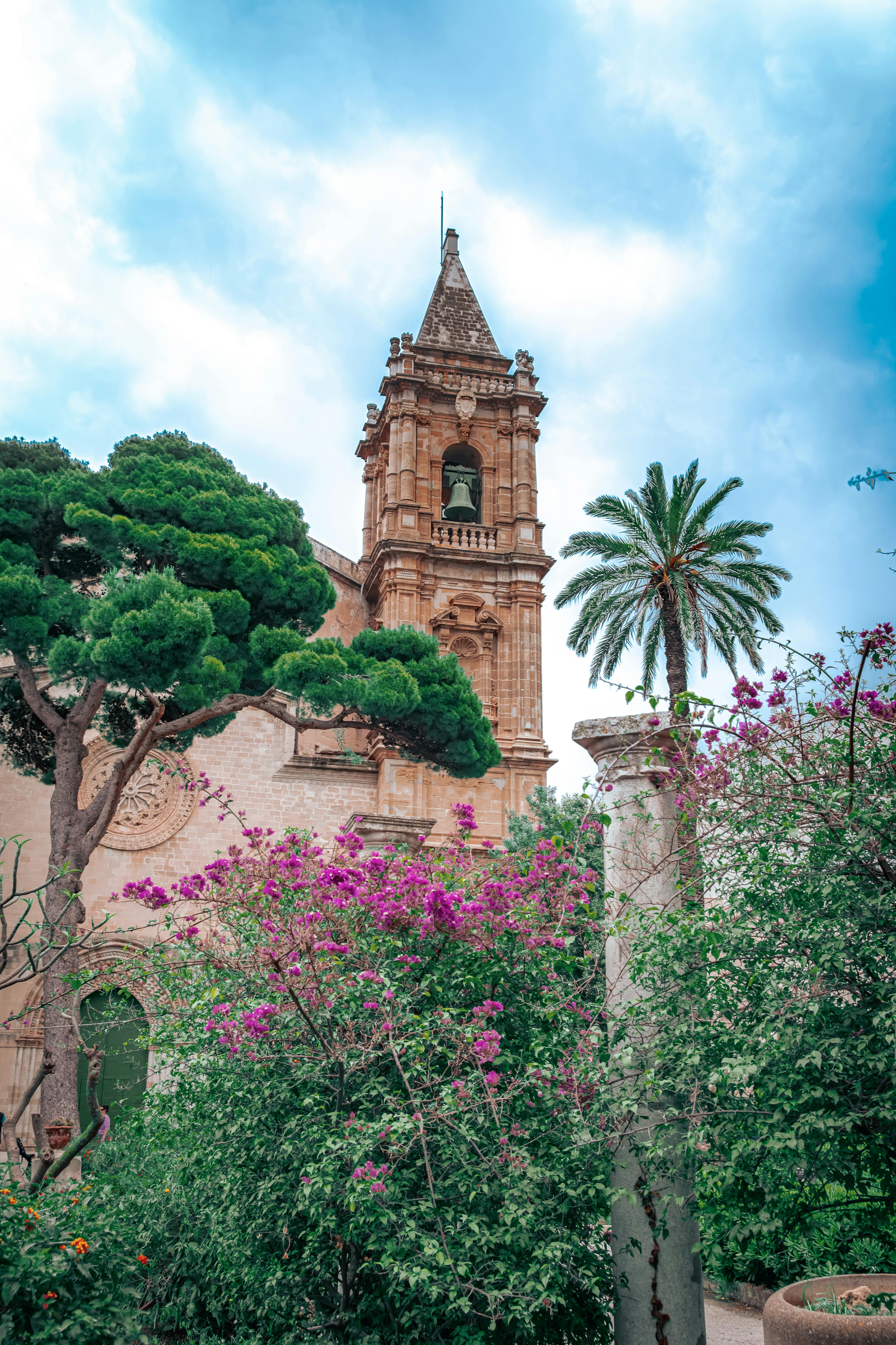 Beautiful church tower with vibrant vegetation in Trapani, Italy.