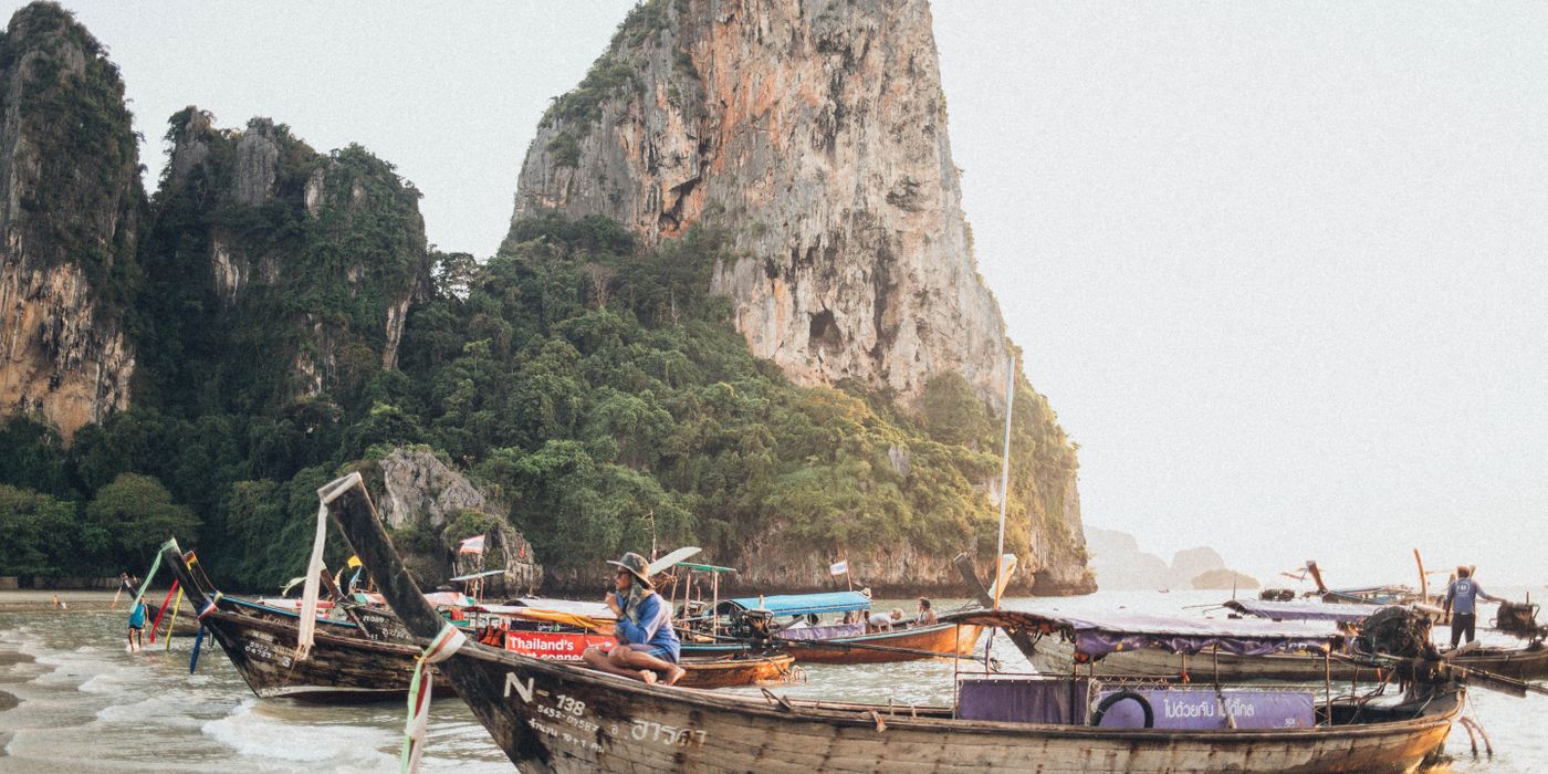 Longtail boats on clear water beneath limestone karsts in Krabi, Thailand
