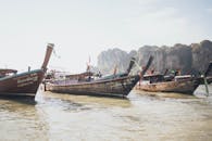 在宁静的泰国港口，传统的长尾船停泊在高耸的石灰石悬崖下