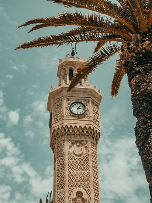 Free A historic Ottoman clock tower surrounded by palm trees in Izmir, capturing its architectural elegance. Stock Photo