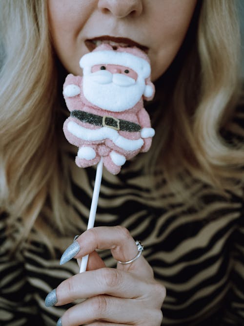 Close-up of Woman Eating a Lollipop in the Shape of Santa Claus 