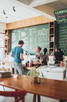 A lively coffee shop scene showing a friendly interaction between a barista and customer, surrounded by cafe decor.