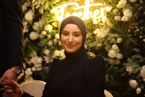 Free Smiling woman in hijab sits against floral background with 'Together' sign. Stock Photo