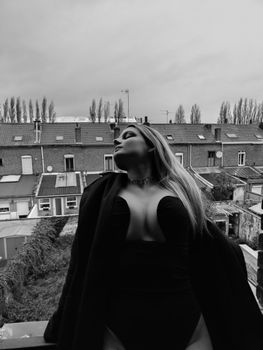 Black and white portrait of a woman posing against a city backdrop.