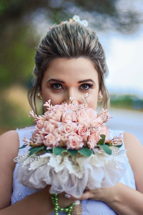 Free A bride poses with a pink bouquet, highlighting floral elegance in an outdoor setting. Stock Photo