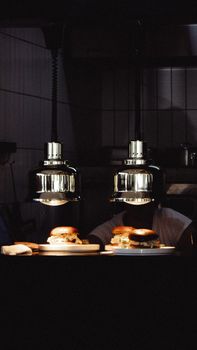 Gourmet burgers illuminated by stylish hanging lamps in a cozy restaurant setting.