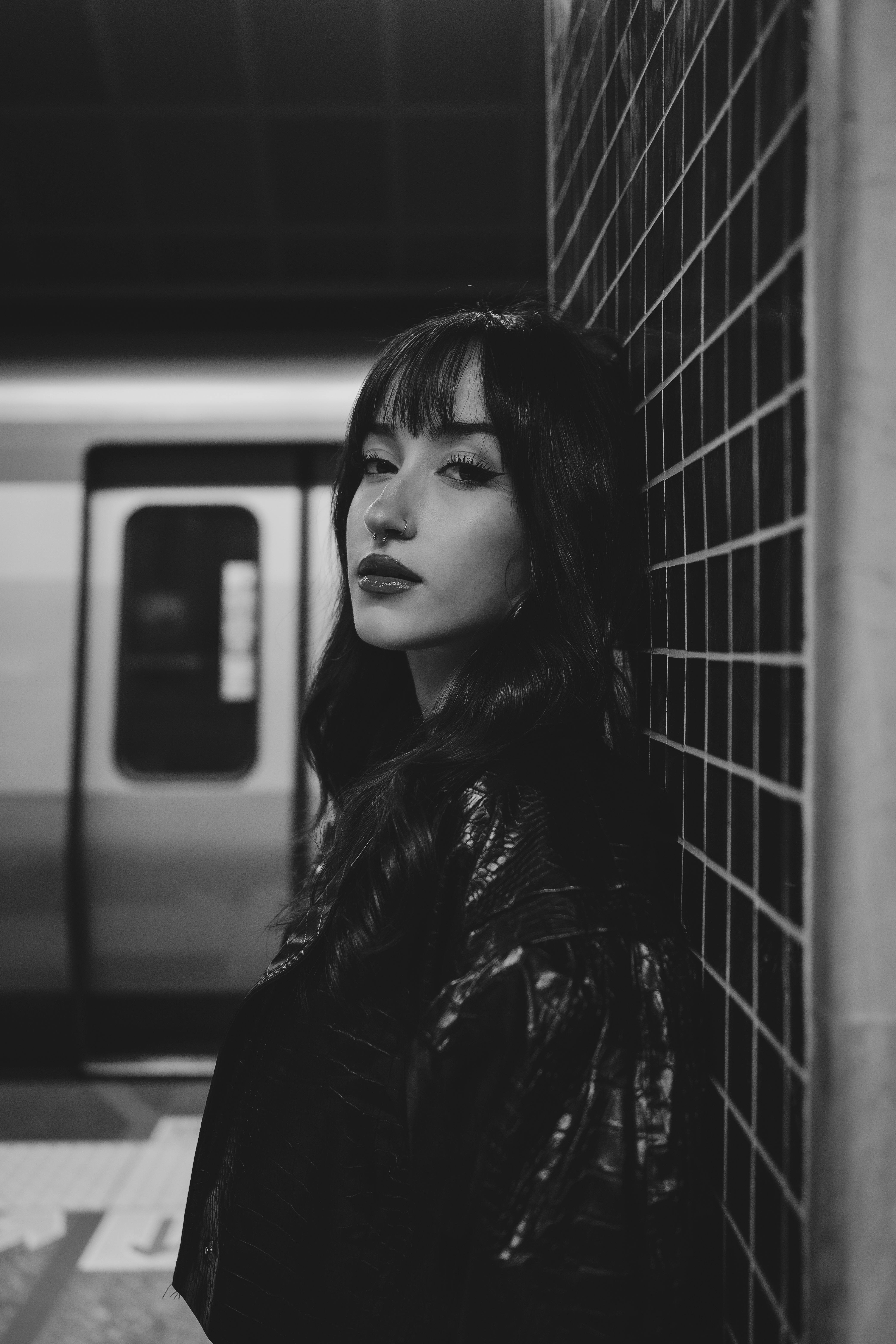 Striking black and white portrait of a woman in a subway station showcasing urban fashion.
