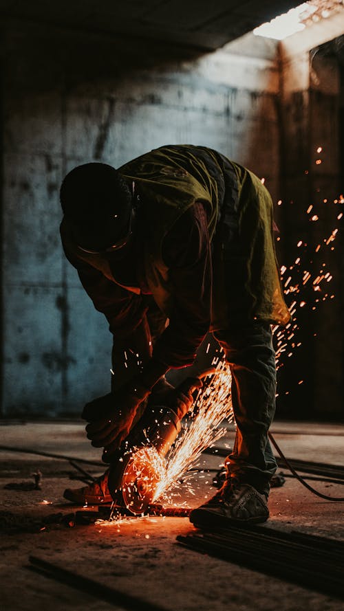 Man Cutting Metal with Sparkles Flying Around 