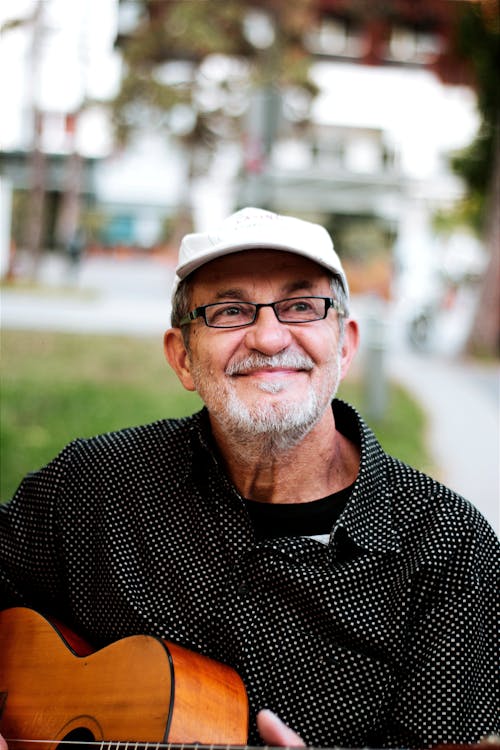 Smiling Man in Cap and Eyeglasses and with Guitar