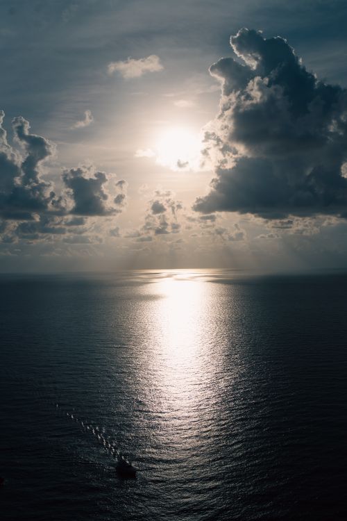 Free A breathtaking aerial view of the sunset reflecting on the ocean on a cloudy day. Stock Photo
