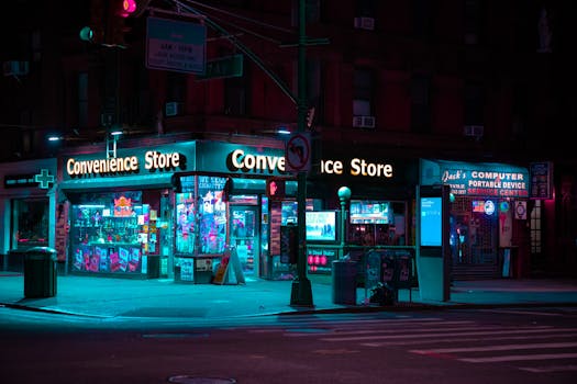 Nighttime view of a neon-lit convenience store in New York City with colorful lighting and empty streets.