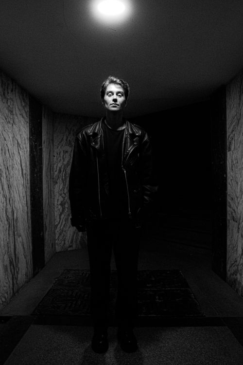 Free Black and white portrait of a man in a leather jacket under a spotlight in a tunnel. Stock Photo