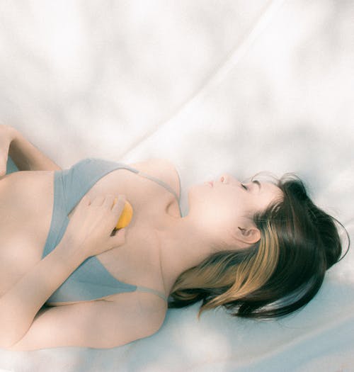 Model in Gray Top Lying with Tangerine