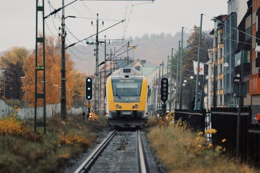 A yellow train travels through autumnal Jönköping, capturing railway and industrial elements.