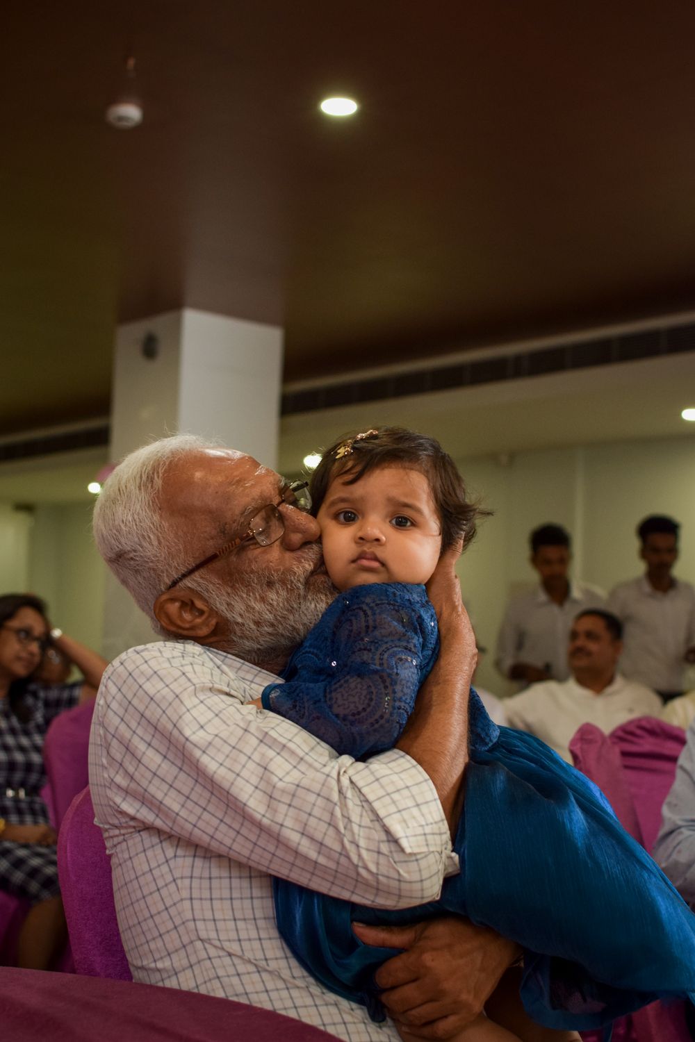 A grandfather kisses his baby granddaughter on the cheek